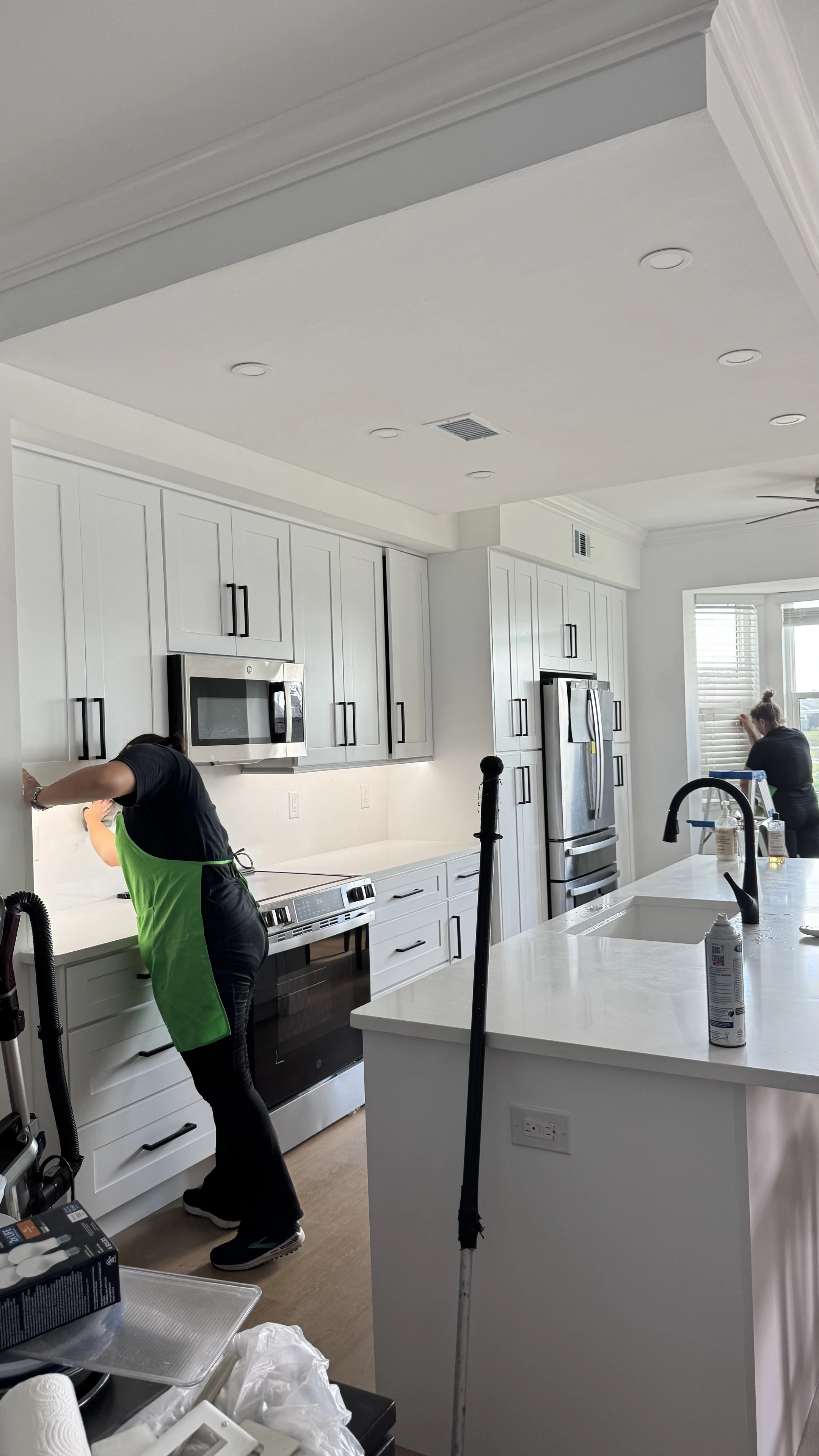 Smart Green team member cleaning a bright kitchen in a green apron